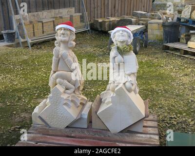 Zwei geschnitzte Statuen, das Tragen der Weihnachtsmann Hüte, sitzen auf einer Palette in der Maurer Hof außerhalb des York Minster. Stockfoto