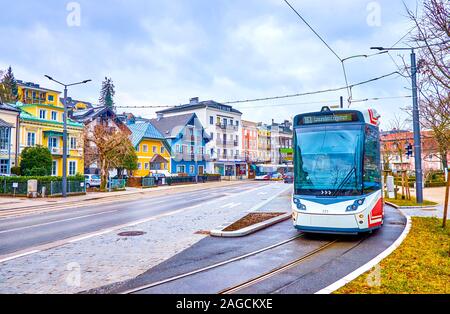 GMUNDEN, Österreich - 22. FEBRUAR 2019: Die moderne Straßenbahn steht an der Haltestelle Kurpark im Wohnquartier in Gmunden, am 22. Februar in Gmunden Stockfoto