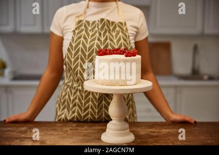 7/8-Ansicht von konditor stehen neben leckeren Kuchen mit johannisbeer auf Tisch Stockfoto