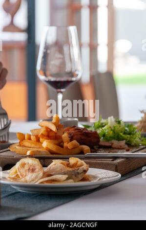 Vertikale Aufnahme einer köstlichen Mahlzeit mit Fleisch, pommes frites und Wein in einem Restaurant in Phnom Penh Stockfoto