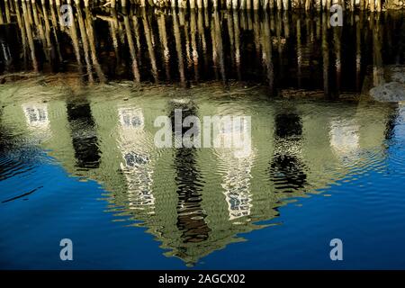 Graues Betongebäude mit weißen Fenstern, die sich im See spiegeln Stockfoto