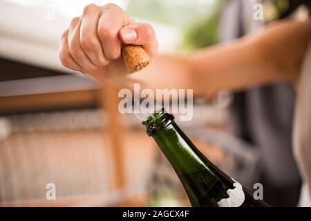 Person öffnet eine Glasflasche Bier mit einem verschwommen Hintergrund Stockfoto