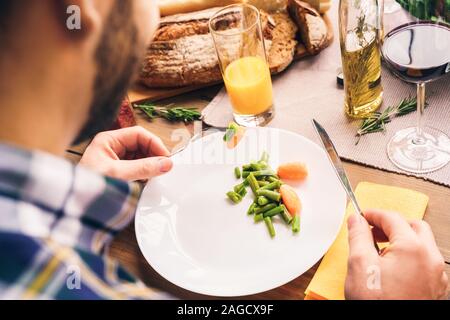 Mann zu Hause hinter Tisch sitzen, essen gesund essen Stockfoto