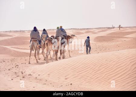 Kamele Wohnwagen in der Wüste Sahara in Tunesien, Afrika. Touristen fahren das Kamel Safari. Kamelkarawane durch die Sanddünen der Sahara Des Stockfoto