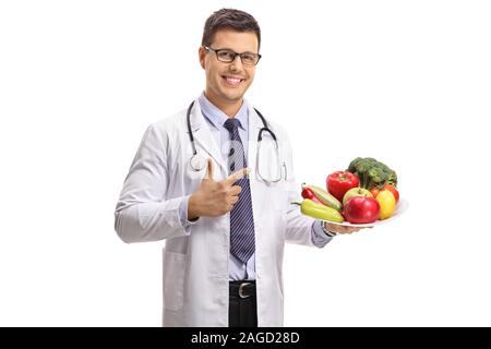 Männlicher Arzt mit einer Platte voller gesunder Früchte und Gemüse auf weißem Hintergrund zeigen Stockfoto