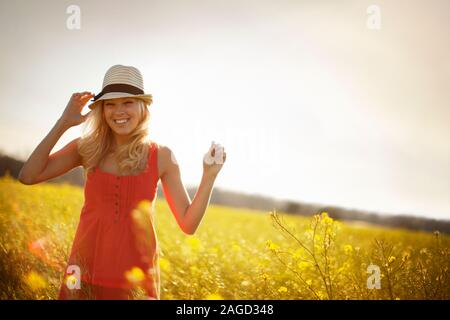 Porträt eines lächelnden jungen Frau mit Hut in einer grünen Wiese. Stockfoto