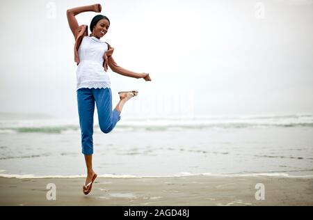 Glückliche junge Frau springen auf einem Strand. Stockfoto