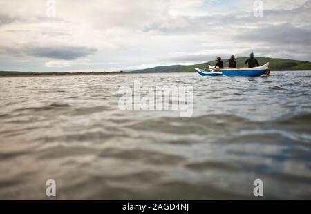 Drei junge Erwachsene zusammen Paddeln in einem Kanu auf dem See. Stockfoto