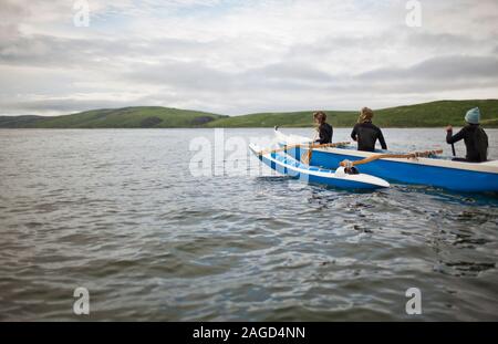 Drei junge Erwachsene zusammen Paddeln in einem Kanu auf dem See. Stockfoto