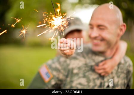 Lächelnd männlichen Soldaten piggy-backing seine junge Tochter in ihrem Hinterhof. Stockfoto