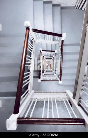 Vertikale Hochwinkelaufnahme einer weißen Treppe mit Holz Handläufe Stockfoto
