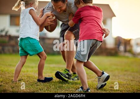 Vater mit seinen Kindern zu spielen in ihrem Hinterhof. Stockfoto