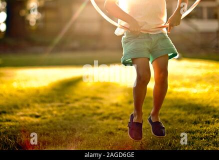 Junge Mädchen durch ein Hula Hoop springen. Stockfoto