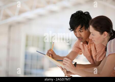 Zwei junge Kolleginnen und Kollegen gemeinsam an einem Projekt arbeiten, Stockfoto