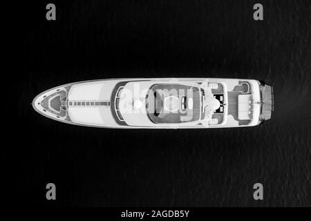 High Angle Graustufen Aufnahme einer weißen Luxusyacht auf Die Meeresoberfläche Stockfoto