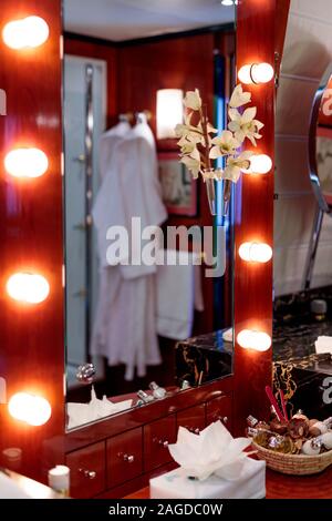 Vertikale Aufnahme eines Konsolenspiegels mit Lampen in einem Hotelzimmer mit Shampoos auf dem Tisch Stockfoto