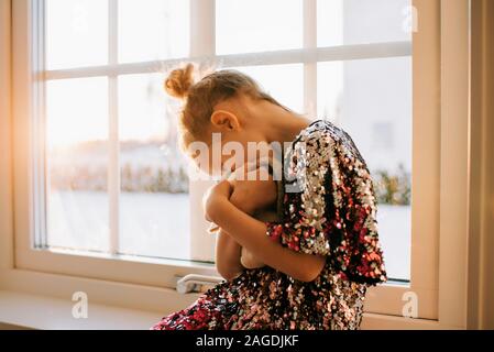 Junge Mädchen spielen mit ihr Spielzeug zu Hause in ein glitzerndes Kleid bei Sonnenuntergang Stockfoto