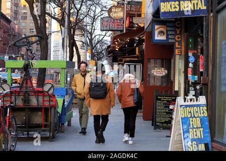 Menschen gehen vorbei an verschiedenen Storefronts auf 9. Avenue in der Küche der Nachbarschaft der Hölle von Manhattan, New York, NY (15. Dezember 2019) Stockfoto