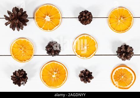 Weihnachten Muster mit Tannenzapfen und getrocknete Orangenscheiben auf weißem Holz- Hintergrund. Frohes neues Jahr. Winter Konzept. Grußkarte. Stockfoto