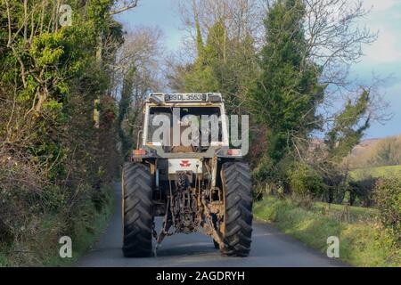 Bauer Fahren des Traktors in Irland. Eine alte weiße Traktor auf einer Landstraße in Irland an einem strahlenden Herbsttag. Stockfoto