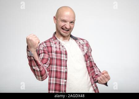 Zufrieden lächelnd Mann ist mit Sieg und Erfolg glücklich, und zeigt eine geballte Faust mit einer Handbewegung. Ja, ich habe es geschafft. Stockfoto