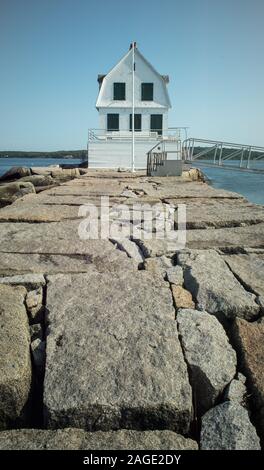 Vertikale Aufnahme eines weißen Holzhauses auf dem Felsen pier am Meer Stockfoto