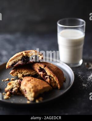 Vertikale Schuss von Cookies mit einer Beerenmarmelade und ein Glas Milch mit verschwommenem Hintergrund Stockfoto