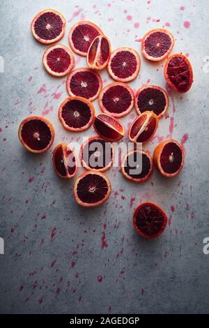 Vertikale Aufnahme von geschnittenen Grapefruits auf einer weißen Oberfläche bedeckt Mit roten Saftflecken Stockfoto