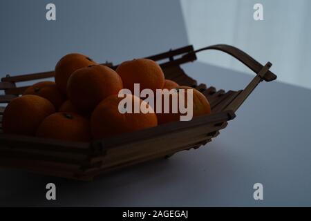 Nahaufnahme von frischen Mandarinen auf einem Holztablett mit Ein grauer Hintergrund Stockfoto