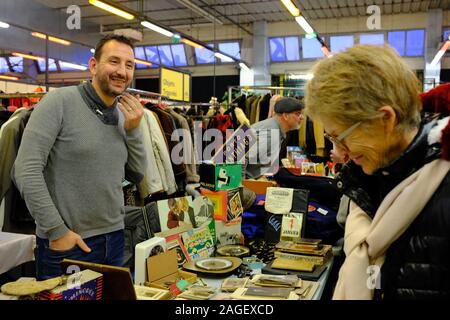 Ein Vintage Kleidung und Haushaltswaren Verkäufer mit Kunden in secondhand Markt in Ground Control. Eine ehemalige SNCF-Lager im 12. arrondissement. Paris. Frankreich Stockfoto