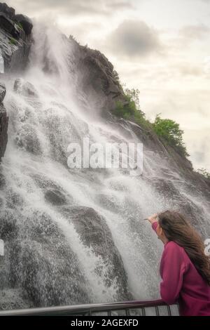 Junge Frau genießt die schöne Hengjanefossen Wasserfall in Forsand, Norwegen Stockfoto