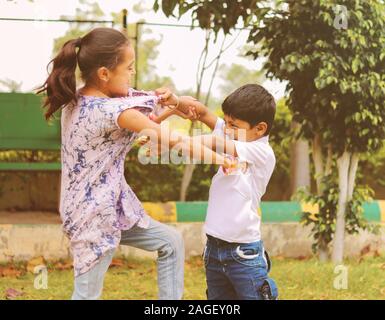 Zwei kleine Geschwister miteinander im Park kämpfen - Kinder schlagen und ziehen Kleid aufgrund von Konflikten in der Schule.