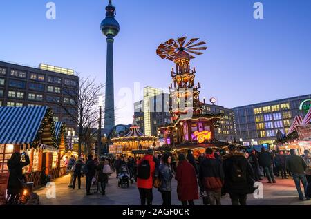 18 Dezember 2019, Berlin: Der Weihnachtsmarkt am Alexanderplatz mit einer großen Pyramide in den Abend in der blauen Stunde. Im Hintergrund das alexanderhaus (L-R), der Fernsehturm, das Berolinahaus und das Kaufhaus Galeria Kaufhof. Foto: Jens Kalaene/dpa-Zentralbild/ZB Stockfoto