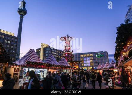 18 Dezember 2019, Berlin: Der Weihnachtsmarkt am Alexanderplatz mit einer großen Pyramide in den Abend in der blauen Stunde. Im Hintergrund das alexanderhaus (L-R), der Fernsehturm, das Berolinahaus und das Kaufhaus Galeria Kaufhof. Foto: Jens Kalaene/dpa-Zentralbild/ZB Stockfoto