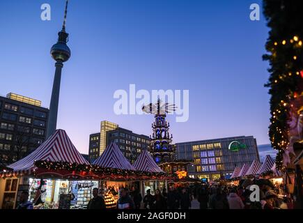 18 Dezember 2019, Berlin: Der Weihnachtsmarkt am Alexanderplatz mit einer großen Pyramide in den Abend in der blauen Stunde. Im Hintergrund das alexanderhaus (L-R), der Fernsehturm, das Berolinahaus und das Kaufhaus Galeria Kaufhof. Foto: Jens Kalaene/dpa-Zentralbild/ZB Stockfoto