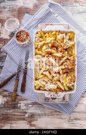 Baked Penne Pasta mit Fleisch, geräuchertem Käse und Gewürzen. Traditionelle italienische Gerichte in Keramik Auflaufform. Vertikaler Dampfstoß Stockfoto