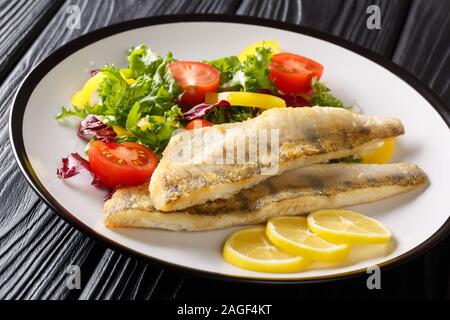 Süßwasser Fisch Filet vom Zander gebraten mit frischem Gemüse und Zitrone close-up in einem Teller auf dem Tisch. Horizontale Stockfoto