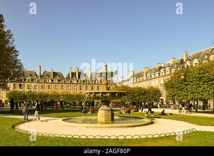 Blick auf den Place des Vosges, berühmten Platz im Marais-viertel, mit einem Steinbrunnen und Menschen entspannend an einem sonnigen Herbsttag, Paris, Frankreich Stockfoto