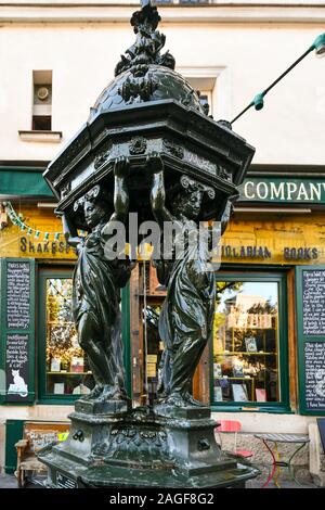 Ein Wallace Brunnen (19. Jahrhundert) vor der berühmten Shakespeare und Company historische Buchhandlung am Seineufer (Rive Gauche), Paris, Frankreich Stockfoto