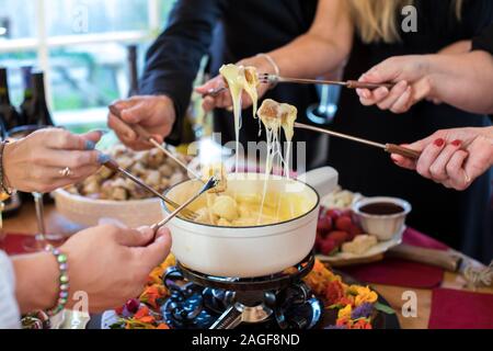 Nahaufnahme der Hände eintauchen Brot mit Käse Fondue Stockfoto