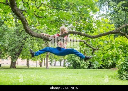 Junge süße Kinder hängen von einem Baum im Sommer Stockfoto