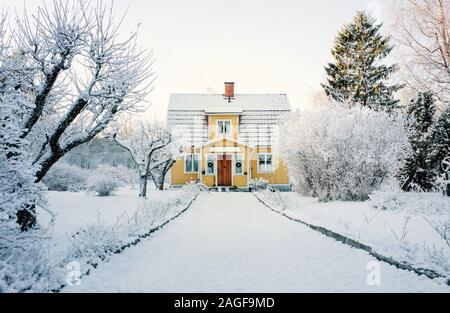 Traditionelle schwedische gelbe Holz abgedeckt im Schnee bei Sonnenuntergang Stockfoto