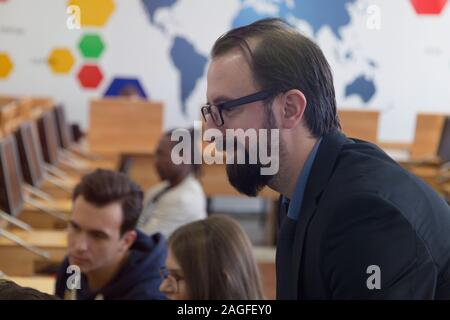 Männliche Professor erklären Lehre für Studenten und mit ihnen interagieren im Klassenzimmer. So ein Schüler während des Unterrichts. Stockfoto