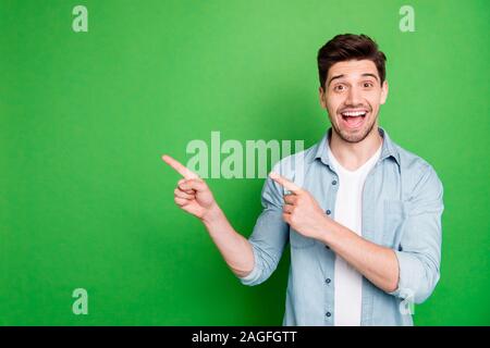 Foto fröhliche, positive schöner Mann zeigte auf leeren Raum ekstatische Gefühle zum Ausdruck auf dem Gesicht mit Borsten über grüne lebendige Farben isoliert Stockfoto