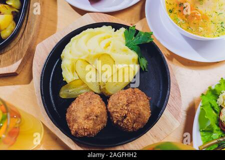 Die Koteletts mit Kartoffelpüree und Gurke auf dem Hintergrund der Esstisch Stockfoto