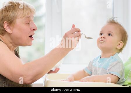 Baby Essen vom Löffel isst Milch Brei Stockfoto