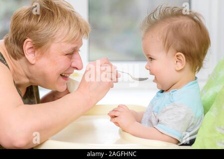 Baby Essen vom Löffel isst Milch Brei Stockfoto