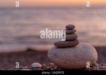 Perfekte Balance von Stapel von Pebbles am Meer in Richtung Sonnenuntergang. Konzept der Balance, Harmonie und Meditation. Helfende oder unterstützende jemand für wachsende oder höher. Stockfoto