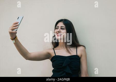 Indische weibliche Outdoor unter selfie mit Smart Handy auf isolierten Hintergrund Stockfoto