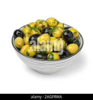 Schüssel mit grünen und schwarzen Oliven, gewürzt mit frischen Kräutern auf weißem Hintergrund Stockfoto